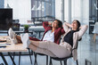 © SERGIO NIEVAS/Westend61 - Smiling female professionals with eyes closed relaxing on chair in coworking office