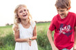 © Wilfried Feder/Westend61 - Cheerful cute girl standing by brother on green field