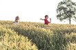 © Wilfried Feder/Westend61 - Smiling boy running in front of sister in green field during sunset