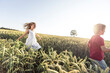 © Wilfried Feder/Westend61 - Smiling girl running behind brother on green field during sunset