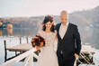 © Daniel Waschnig Photography/Westend61 - Bride and groom walking on jetty over lake