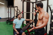 © Eva Blanco/Westend61 - Smiling sportsman looking at friend while sitting by exercise equipment in gym