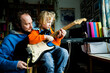 © Irina He√ü/Westend61 - Father teaching electric guitar to blond son while sitting at home