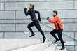 © JOSEP SURIA/Westend61 - Athletic man and woman running up on steps by wall