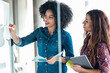 © JOSEP SURIA/Westend61 - Young female professional discussing over white board with female colleague at office