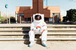 © Eugenio Marongiu/Westend61 - Male astronaut in space suit sitting on steps during sunny day