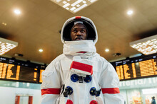 Male Astronaut Wearing Space Suit Standing At Arrival Departure Board