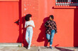 © Eugenio Marongiu/Westend61 - Multi-ethnic friends talking while leaning on red building