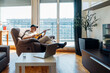 © Eugenio Marongiu/Westend61 - Man playing guitar while sitting on reclining chair at home