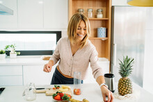 Happy Woman With Fruits On Kitchen Island At Home
