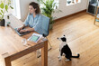 © steve brookland/Westend61 - Dog looking at female entrepreneur working on laptop at home office