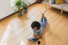Woman Using Laptop While Resting On Floor At Home