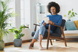 © steve brookland/Westend61 - Smiling woman reading book while sitting on armchair at home
