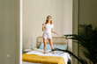 © Xavier Lorenzo/Westend61 - Woman dancing on bed while listening music through headphones at home