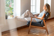 © steve brookland/Westend61 - Woman with coffee mug relaxing on chair at home