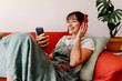 © Tania Cervian/Westend61 - Smiling woman listening music while using mobile phone on sofa