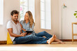 © steve brookland/Westend61 - Beautiful woman looking at boyfriend using digital tablet while sitting on floor at home
