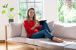 © steve brookland/Westend61 - Contented woman with digital tablet sitting on couch at home