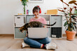 © Tania Cervian/Westend61 - Young woman wearing headphones sitting with laptop and cat at home