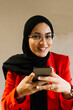 © Xavier Lorenzo/Westend61 - Smiling woman wearing hijab holding mobile phone at cafe