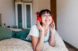 © Tania Cervian/Westend61 - Beautiful woman wearing headphones smiling while lying on front in bed