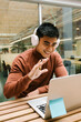© Xavier Lorenzo/Westend61 - Smiling male entrepreneur waving hand during video call on laptop at cafeteria