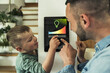 © Uwe Umstatter/Westend61 - Boy adjusting lights on digital tablet with father at smart home