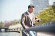 © Uwe Umstatter/Westend61 - Businessman checking time on wristwatch while leaning on railing