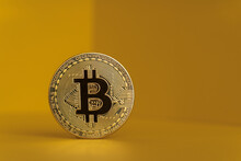 Gold colored bitcoin against yellow background