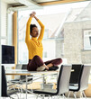 © Uwe Umstatter/Westend61 - Female professional with arms raised meditating on desk at office