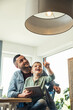 © Uwe Umstatter/Westend61 - Smiling boy pointing at pendant light while sitting with father in smart home