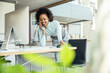 © Uwe Umstatter/Westend61 - Smiling businesswoman leaning on desk while talking on mobile phone at office