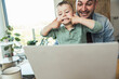 © Uwe Umstatter/Westend61 - Boy teasing while sitting with father doing video call through laptop at home