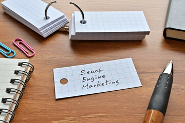 Poster - There is a word book with the word Search Engine Marketing written on it with a pen and notebook.