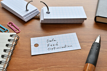 Poster - There is a word book with the word Data Feed Optimization written on it with a pen and notebook.