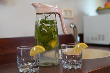 Canvas Print - Decanter of cold water with lemon and mint on a wooden table