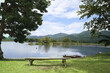 Wooden chairs are placed by the river for outdoor view with blue sky over the mountain and lake view on background. Bench on the lake for Sit and relax in a shady atmosphere amidst nature.