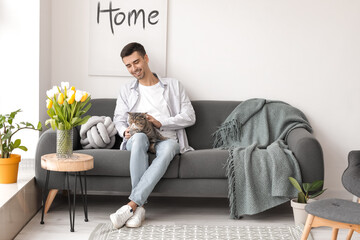 Young man with cute cat in living room