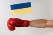 Boxing glove with Ukrainian flag. Boxer holds flag of Ukraine. White background.