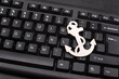 Black computer keyboard and anchor. Close up