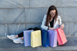 Girl sits on the stairs and considers purchases in colored bags. After successful shopping