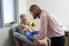 Mature Woman In Phlebotomy Chair With Nurse Taking Blood Test