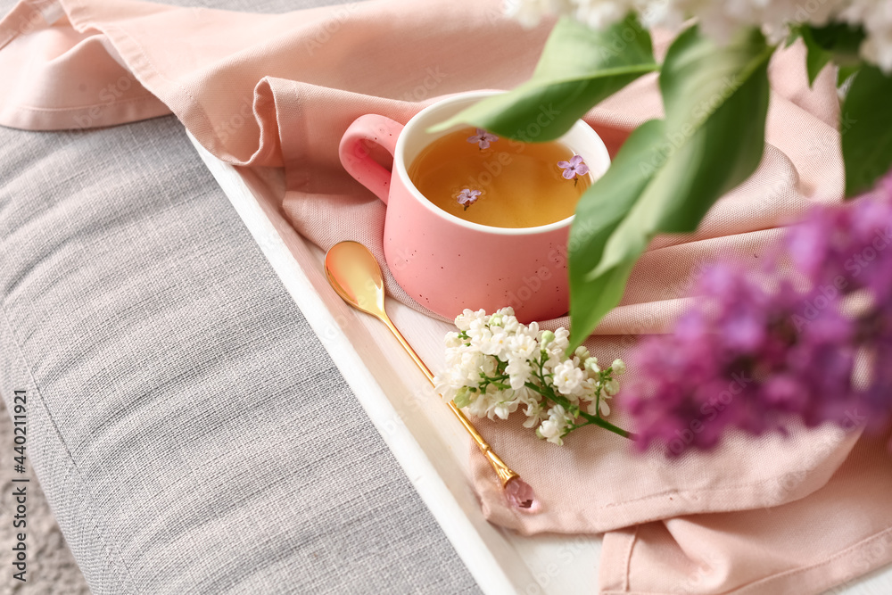 Cup of tea with spoon and lilac flowers, closeup