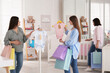 Happy pregnant women with shopping bags choosing baby clothes in store