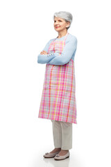 Poster - cooking, culinary and old people concept - portrait of smiling senior woman in kitchen apron with crossed arms over white background