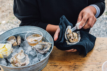 woman shucking oysters at outdoor restaurant