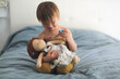 Girl child makes an injection with a wooden syringe to a doll on the bed in the bedroom, the concept of vaccination and childcare, care. Role-playing games with dolls for toddlers