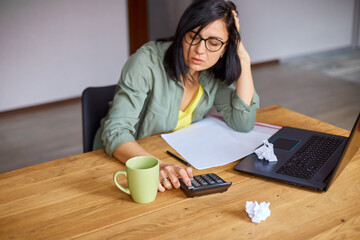 Woman accountant sit calculate expenses on calculator at wooden table, modern workplace