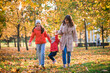 © irishasel - Mother and daughter having fun in the autumn park among the falling leaves. Active lifestyle