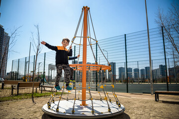 Wall Mural - Two young boy active little child playing climbing at spring metal playground his hand to exercise at outdoor. Warm sunny day. Friendship concept